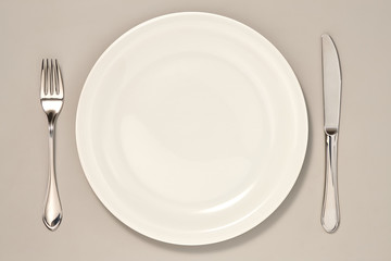 Empty Plate, Knife and Fork isolated on Grey Background with Real Shadow. Top View