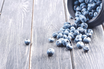 Fresh blueberries in the bowl on a wooden table. Top view