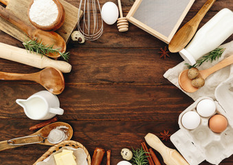 Baking or  recipe ingredients (eggs, flour, milk, butter, sugar) on wooden table from above. Background layout with free text space.