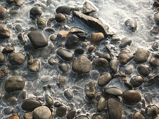 Close up of frozen water with stones in the river