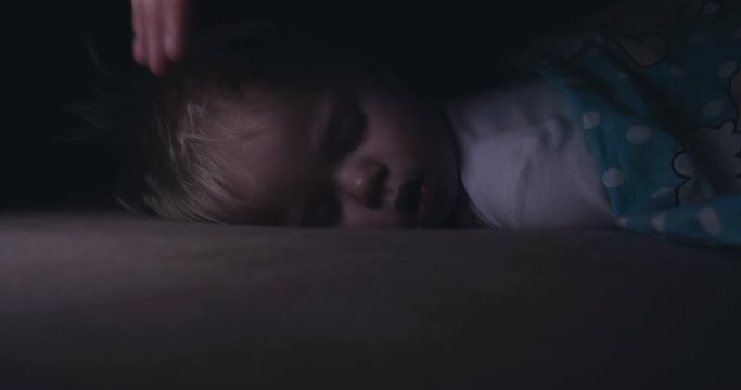 Little baby boy sweetly sleeps in bed, dad puts his son to bed.