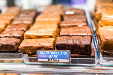 Macro closeup of chocolate marshmallow bars candy sweet dessert treats with sign on tray display in store, shop, bakery, cafe