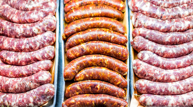 Flat Lay Down Top View Pattern Of Many Raw Artisan Sausages Pink, Red, Orange Chorizo Closeup On Tray In Fresh Market Butcher Shop Store