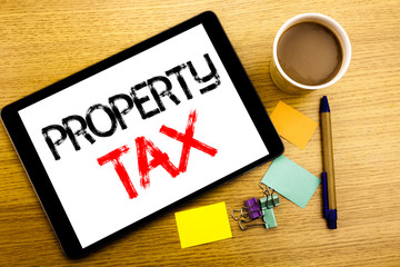 Handwritten text caption showing Property Tax. Business concept writing for Estate Income Taxation Written on tablet laptop, wooden background with sticky note, coffee and pen