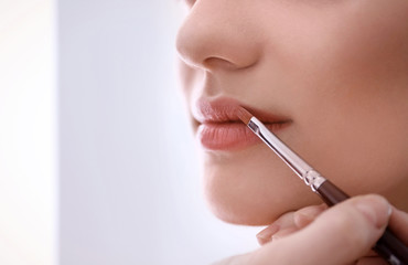 Professional makeup artist working with woman, indoors