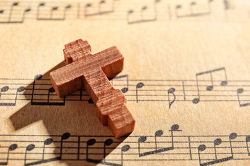 Naklejka premium Wooden cross on music sheet