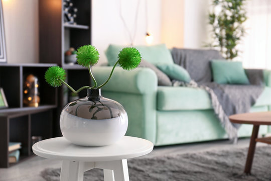 Vase with plant on small table in living room