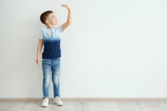 Little Boy Measuring Height Near Light Wall