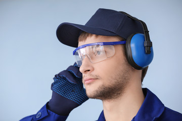 Male worker with headphones on grey background. Hearing protection equipment