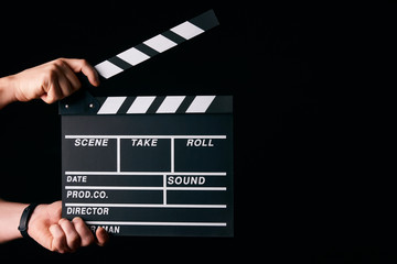 Hands with a movie clapperboard isolated on black background with copy space, close-up. Wooden...