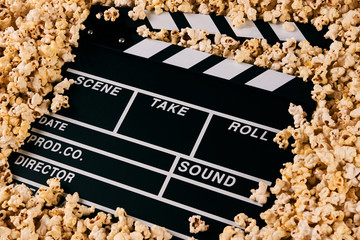 Clapper board and pop corn. Black wooden movie clapper with sweet popcorn, close-up. Movie time...