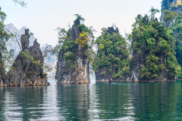Fototapeta na wymiar Significant karst formations in the national park Khao Sok rise above the Cheow Lan Lake. The Khao Sam Kler rocks of the Khao Sok national park are national symbols