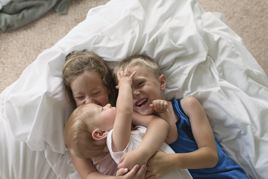 High angle view of happy siblings lying on bed at home