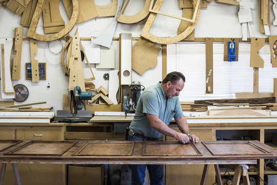 Carpenter Polishing Wood While Working At Workshop