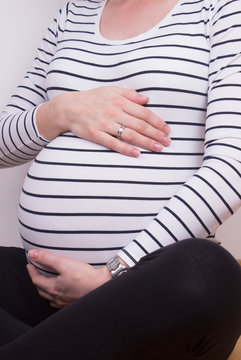 young woman touching her own pregnant belly