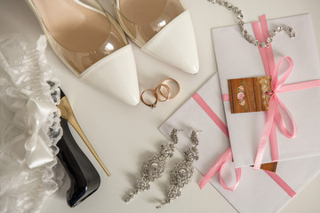 Wedding shoes for bride near one engagement ring and two wedding rings for bride and groom, bridal jewelry, garter and wedding invitation . Marriage concept