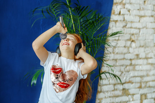 An emotional child listens to music and sings. The concept is childhood, lifestyle, music, singing, listening, hobbies.