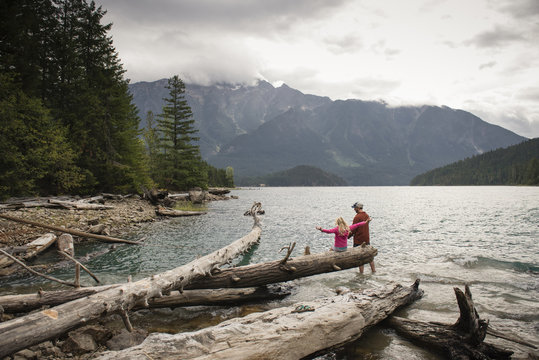 Rear view of father and daughter fishing in river against mountains