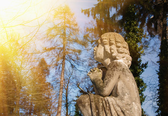 Fototapeta na wymiar Olld stone angel in prayer to heaven (religion, baby angel, faith concept)