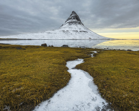 Idyllic view of snowcapped mountain against stormy clouds by lake