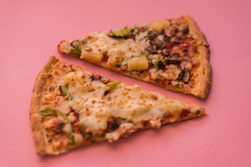 two slices of pizza on a pink background