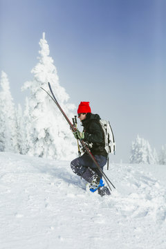 Side view of hiker with backpack and ski walking on snowy hill during winter