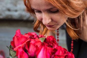 Beautiful redhead Caucasian girl smelling colorful flowers in the garden 
