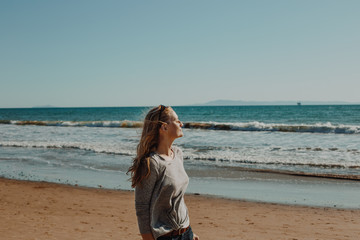 Obraz na płótnie Canvas Blonde Woman at the Beach with Wind in Hair and Sun