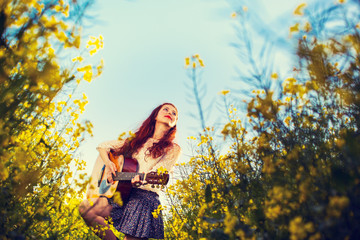Young ginger hair girl in 70s style with acoustic guitar