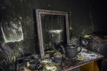 Burnt room interior. Burnt still life. Charred wall, picture frame, pot with burned rose in black...