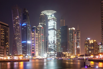 Fototapeta na wymiar DUBAI, UAE - FEBRUARY 2018: Colorful evening on canal and promenade in Dubai Marina,Dubai,United Arab Emirates