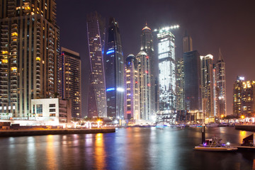 Obraz na płótnie Canvas DUBAI, UAE - FEBRUARY 2018: Colorful evening on canal and promenade in Dubai Marina,Dubai,United Arab Emirates