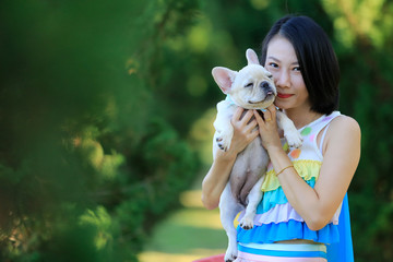 Portrait Of A Young Woman holding a French bulldog in her arms. With copy space.