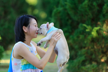 A woman kisses small pet a French Bulldog puppy. with copy space.