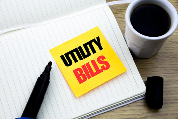 Hand writing text caption inspiration showing Utility Bills. Business concept for Money Bill Payment written on sticky note paper, Wooden background with space, Coffee and marker