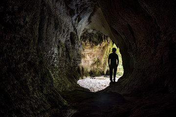Fototapeta na wymiar Silhoutte of Hiker in huge mysterious cave, Oparara Basin, Moria Gate Arch