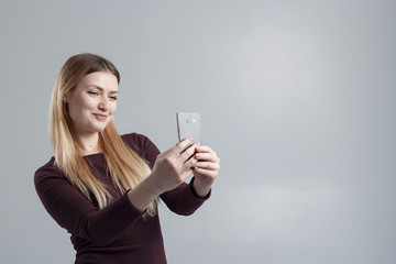 The girl makes selfie on the phone on a gray background, isolate