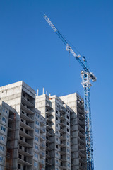 cranes over a high block-of-flats on the blue sky background