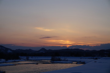 冬の夕暮れ　川　日没　雪景色　太陽