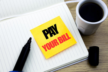 Hand writing text caption inspiration showing Pay Your Bill. Business concept for Payment for Goverment written on sticky note paper, Wooden background with space, Coffee and marker