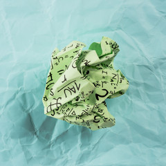 Crumpled multi colored paper balls with mathematical equations on multi colored plain paper, with...