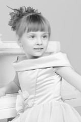 A girl is posing near a white grand piano.