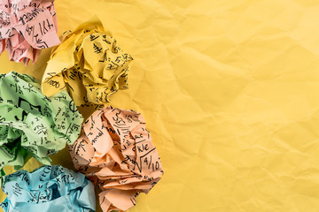 Crumpled multi colored paper balls with mathematical equations on multi colored plain paper, with...