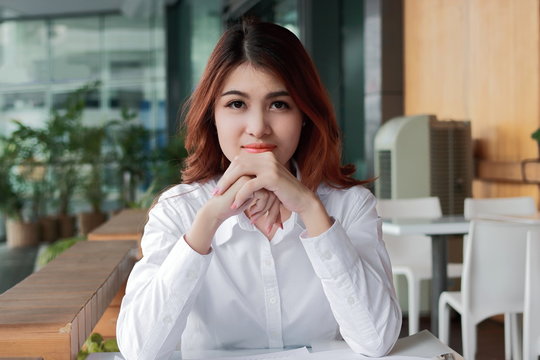 Portrait of confident young Asian businesswoman looking on camera at workspace in office background. Leadership woman concept.