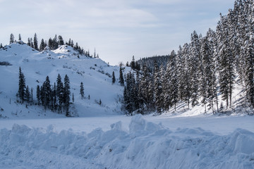 Winter landscape in the mountains with blue sky and snow-capped peaks and forest