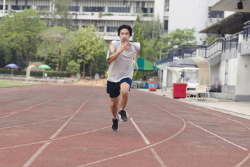 Handsome athlete Asian man running on racetrack in stadium with copy space background. Healthy...