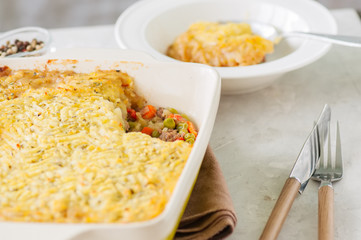 Shepherds pie -  Irish traditional food. Served in a ceramic dish on a white stone background.