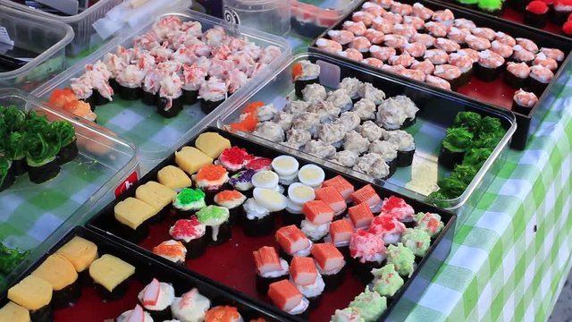 Street food : various kinds of sushi served for sell at night food market in island Koh Phangan, Thailand. Close up