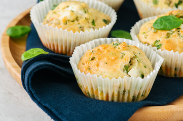 Savory muffins with feta cheese and spinach on a wooden plate on a wire rack.White stone backdrop.