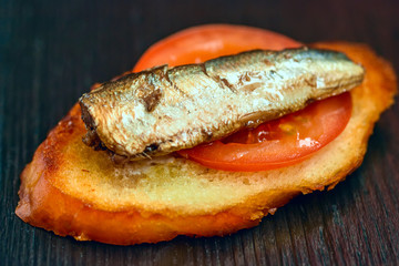 sandwich with sprats on a dark wooden background